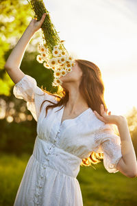 Portrait of smiling young woman with arms raised standing outdoors