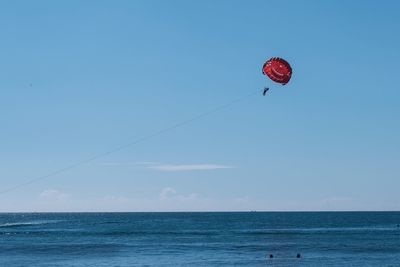 Man paragliding over sea against sky