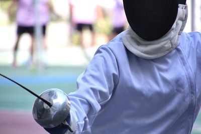 Rear view of man standing on guard for fencing sports 