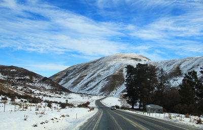 Road amidst snowcapped mountains against sky