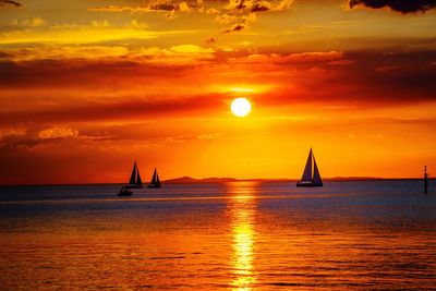 Scenic view of sea against orange sky and a setting sun