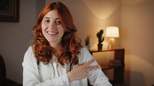 Beautiful italian woman doctor makes the symbol of the anti covid 19 vaccine.