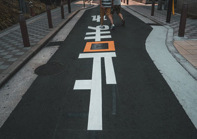 Low section of people walking on footpath with markings