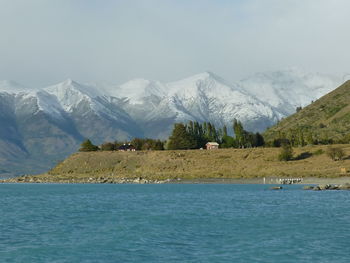 Scenic view of lake by snowcapped mountains against sky