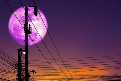 Low angle view of electricity pylon against sky during sunset