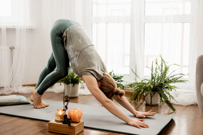 Beautiful young woman doing exercises and doing yoga at home