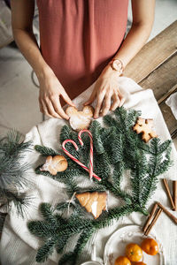Preparation for the new year, holiday cookies. female hands put red lollipops on spruce branches