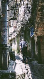 Rear view of person walking on footpath amidst buildings