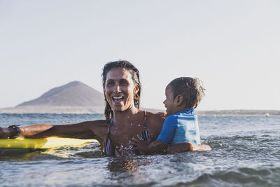 Smiley young mother and son playing at sea