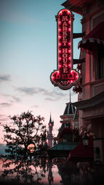 Low angle view of illuminated lanterns hanging by building against sky