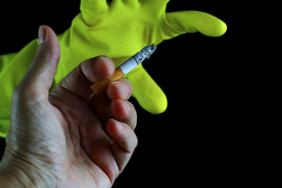 Close-up of hand holding leaf against black background