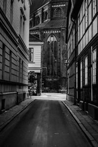 Empty road amidst buildings in city