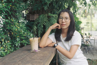 Portrait of young woman holding eyeglasses on table