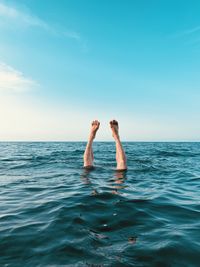 Low section of woman in sea against sky