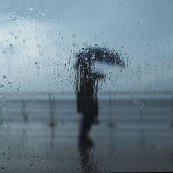 Person seen through wet glass window in rainy season