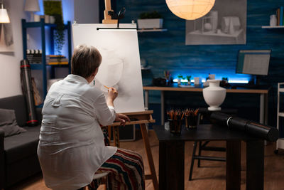 Rear view of woman standing by table at cafe