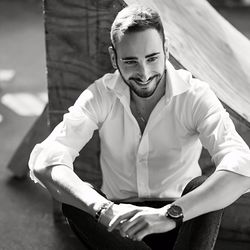 High angle view of smiling thoughtful young man sitting outdoors