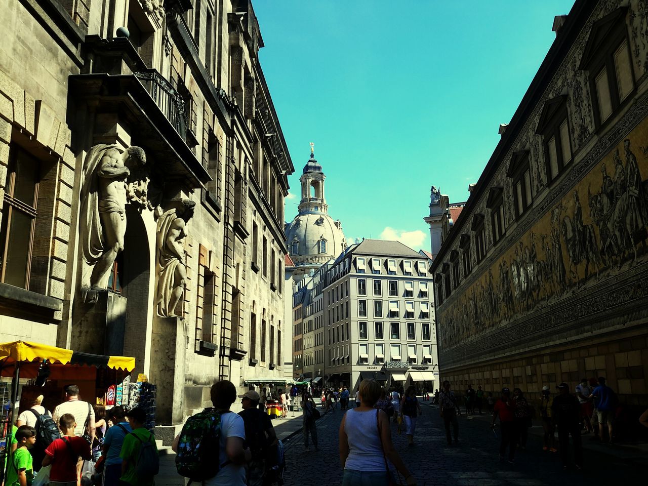 architecture, building exterior, built structure, large group of people, person, men, street, lifestyles, city, walking, city life, crowd, leisure activity, mixed age range, building, clear sky, old town, day, residential building