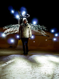 Full length of woman holding illuminated umbrella at night