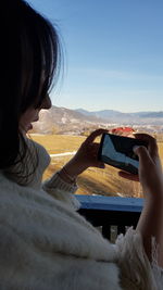 Midsection of woman photographing against sky