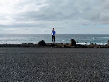 Rear view of man standing on beach against sky