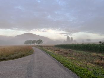 Road amidst field against sky