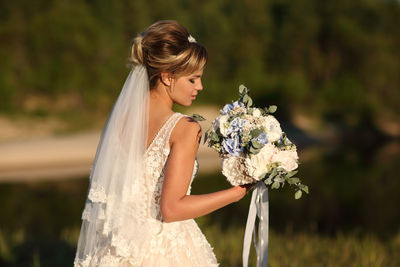 Bride with a bouquet of flowers on the background of the river