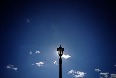 Low angle view of silhouette statue against blue sky