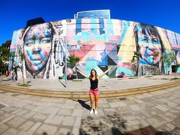 Full length of woman standing against graffiti in city