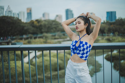 Portrait of young woman standing against railing