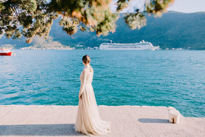 Rear view of woman standing against sea