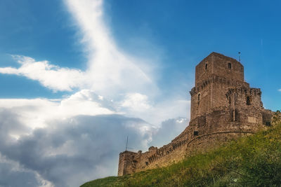 An extraordinary pattern of clouds over a big fortress in assisi.