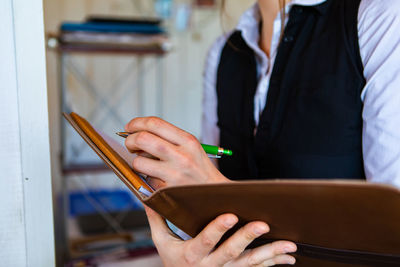 Midsection of women holding file