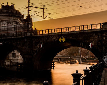 Arch bridge over river during sunset