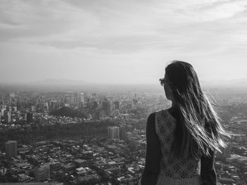 Woman looking at cityscape against sky