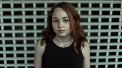 Portrait of young woman standing against wall