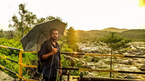 Man standing by railing against sky