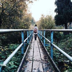 Rear view of man walking on footbridge