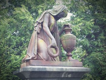 Close-up of old statue against trees