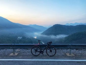 Bicycle on railing against mountains