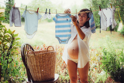 Pregnant woman hanging baby clothes on clothesline