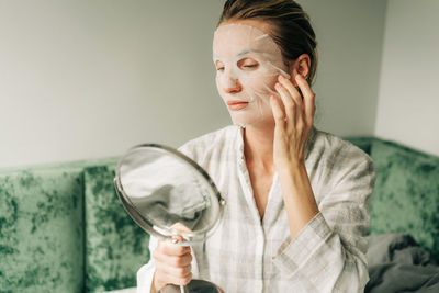 A woman uses a textile facial moisturizing mask.