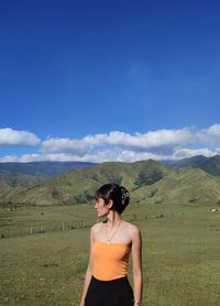 Rear view of woman standing on field against sky