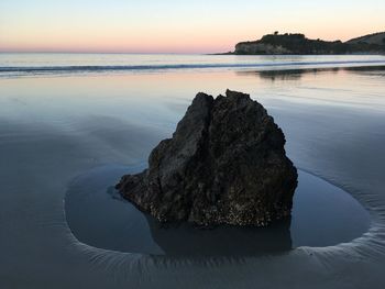 Rock formation on sea against sky during sunset