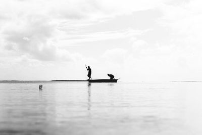 Silhouette man in sea against sky