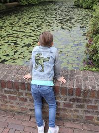 Rear view of boy standing against wall