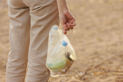 Midsection of woman holding bottle