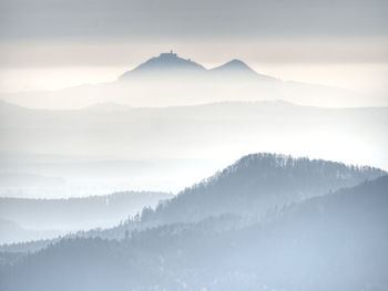 Outlines of forest hills hidden in thick mist. cold and damp morning in autumn hill sides and peaks.