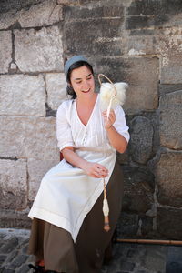 Full length of a smiling young woman against wall