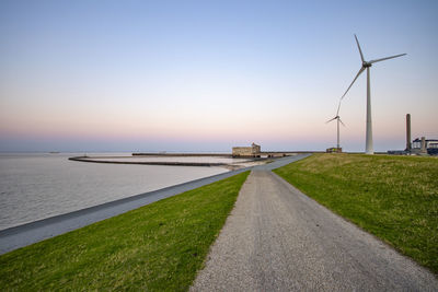 Empty road by sea against clear sky